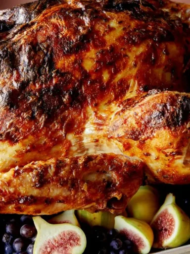 Juicy mayo roasted turkey with paprika browned skin surrounded by figs and grapes on a platter